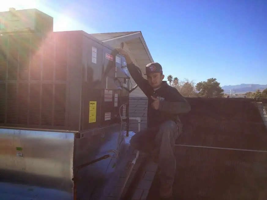 HVAC technician performing Air Duct Repair on a rooftop unit in East Ridge